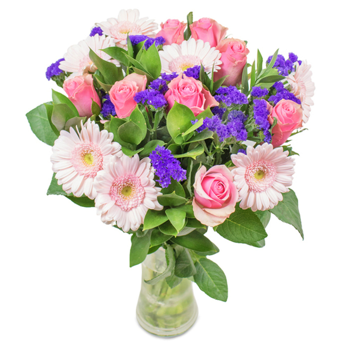 A vibrant bouquet crafted in the heart of Camberwell, this arresting floral arrangement is thoughtfully styled in a clear glass vase and set against a clean, crisp background. The bouquet features approximately eight soft to medium pink roses-some tightly furled, others gracefully unfurling-displaying the spiral symmetry iconic to rose blooms. Intermixed are five to seven pale pink gerberas, their large rounded heads and radiating petals providing gentle contrast, each with a bright center that softly blends to near-white. Scattered throughout, clusters of vivid purple statice add texture and a pop of deeper colour, reminiscent of blooms found at local Camberwell shops and markets. A foundation of lush, dark green foliage creates a sense of abundance and freshness, recalling the green spaces lining the local high streets. Visible through the vase's transparent walls, the sturdy stems and clear water reinforce a commitment to local, just-delivered freshness. Suitable for occasions from birthdays and anniversaries to thoughtful tokens of affection for a Camberwell resident, this bouquet is expertly crafted to convey joy, celebration, and heartfelt connection.